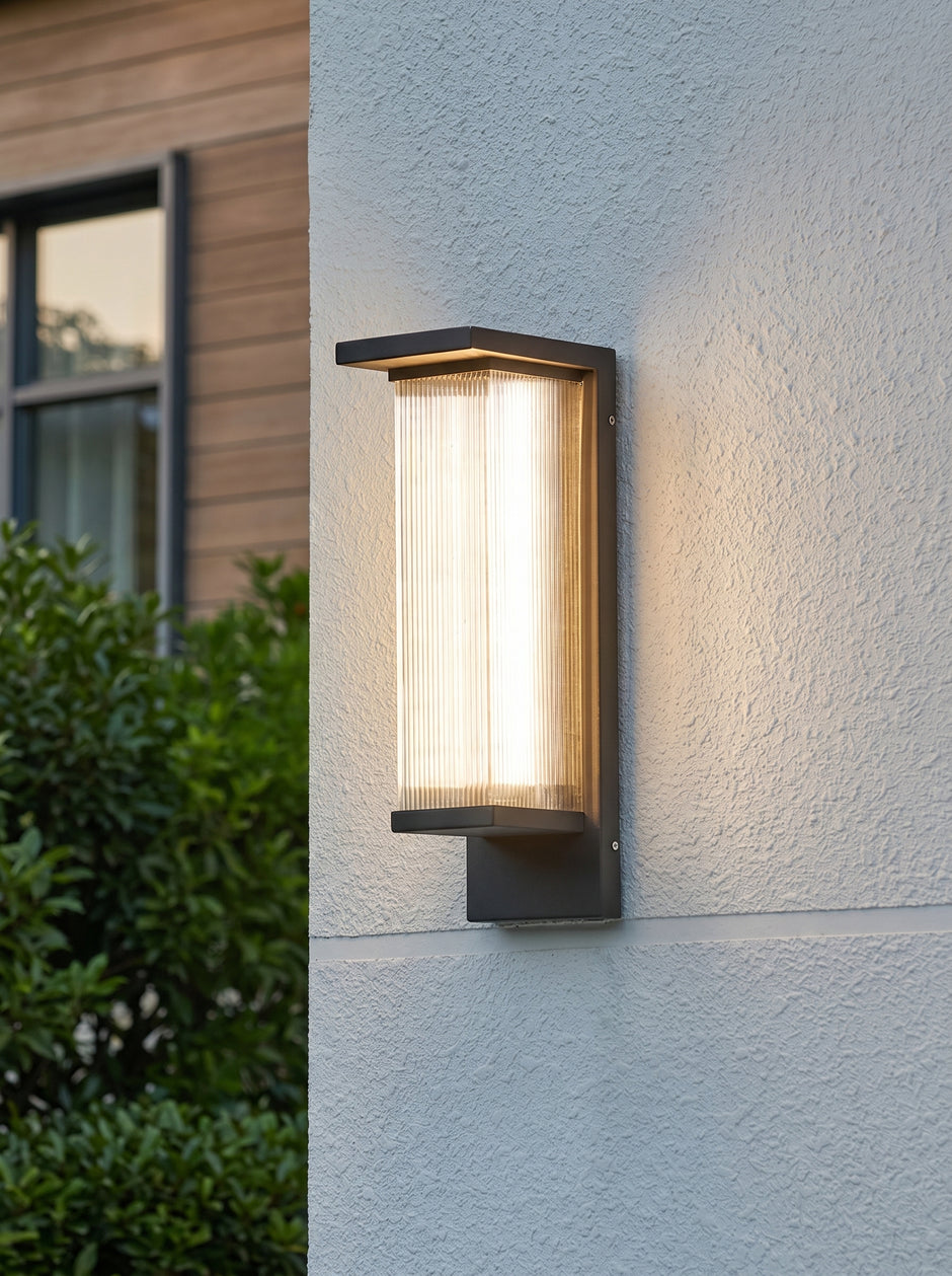 AI Studio Photo - Standing facing the camera, natural confident posture, arms relaxed at sides, front view, full body visible. CAMERA SHOT: A medium shot focusing on the wall lamp mounted on a textured exterior wall, showcasing its design and the light it emits. [Full body]