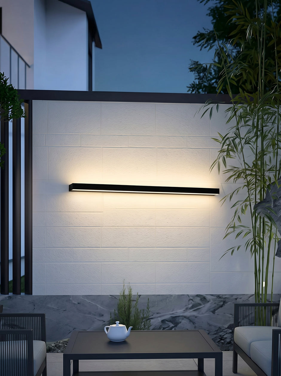AI Studio Photo - Standing facing the camera, natural confident posture, arms relaxed at sides, front view, full body visible. CAMERA SHOT: A medium shot focusing on the wall lamp and its illuminated effect, with a hint of the surrounding outdoor patio setting. [Half body styled]
