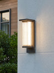 AI Studio Photo - Standing facing the camera, natural confident posture, arms relaxed at sides, front view, full body visible. CAMERA SHOT: A medium shot focusing on the wall lamp mounted on a textured exterior wall, showcasing its design and the light it emits. [Full body]
